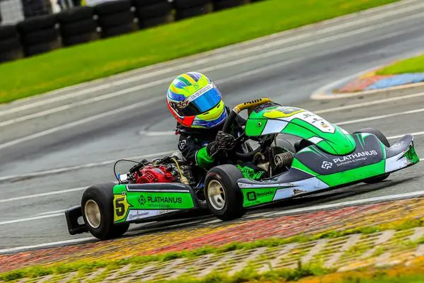 Enrico de capacete verde e azul em uma curva da pista, pilotando um kart verde com o número 5