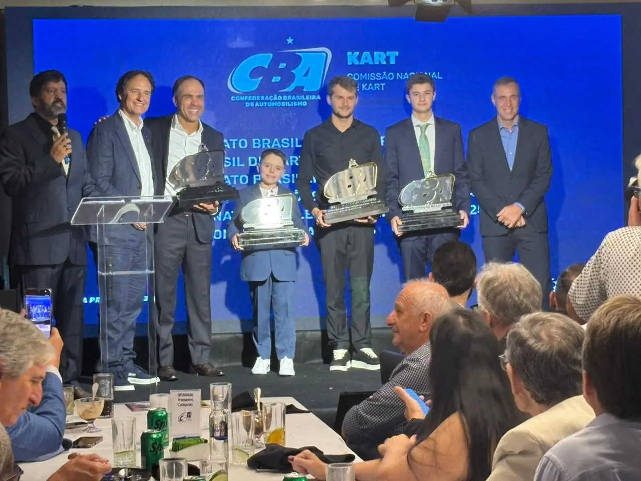 Premiados da CBA Kart em um palco, segurando troféus, durante a cerimônia