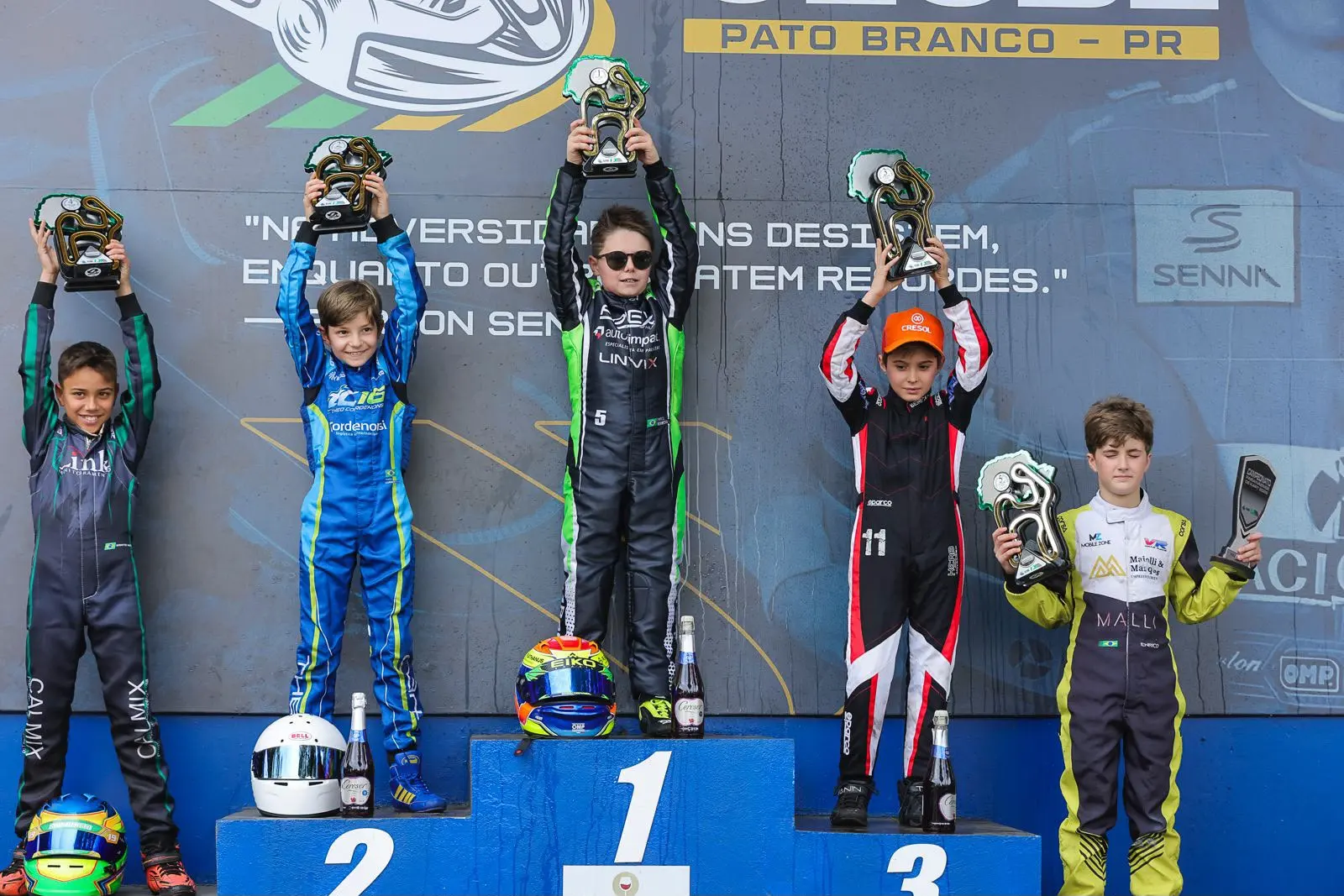 Enrico no alto do pódio do Campeonato Paranaense, de óculos escuros e com o troféu erguido, em Pato Branco (PR)